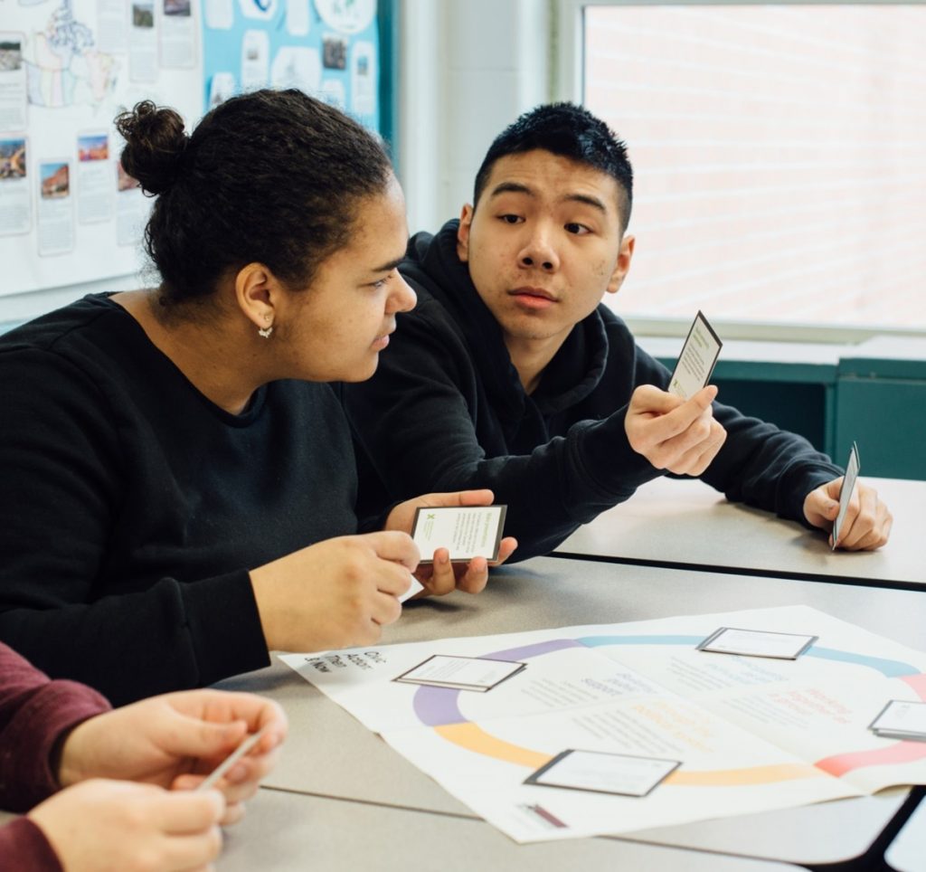 Two students look at cards with historical event descriptions on them, and decide where to place them on the activity map.