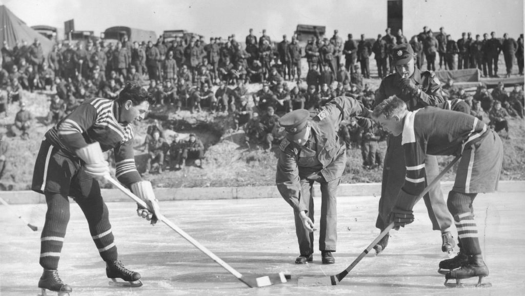 Two hockey players leaned over centre ice waiting for the puck to drop. 